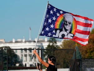 caption: A woman waves a Joe Biden flag during celebrations of his presidential victory on Black Lives Matter Plaza across from the White House on Saturday.
