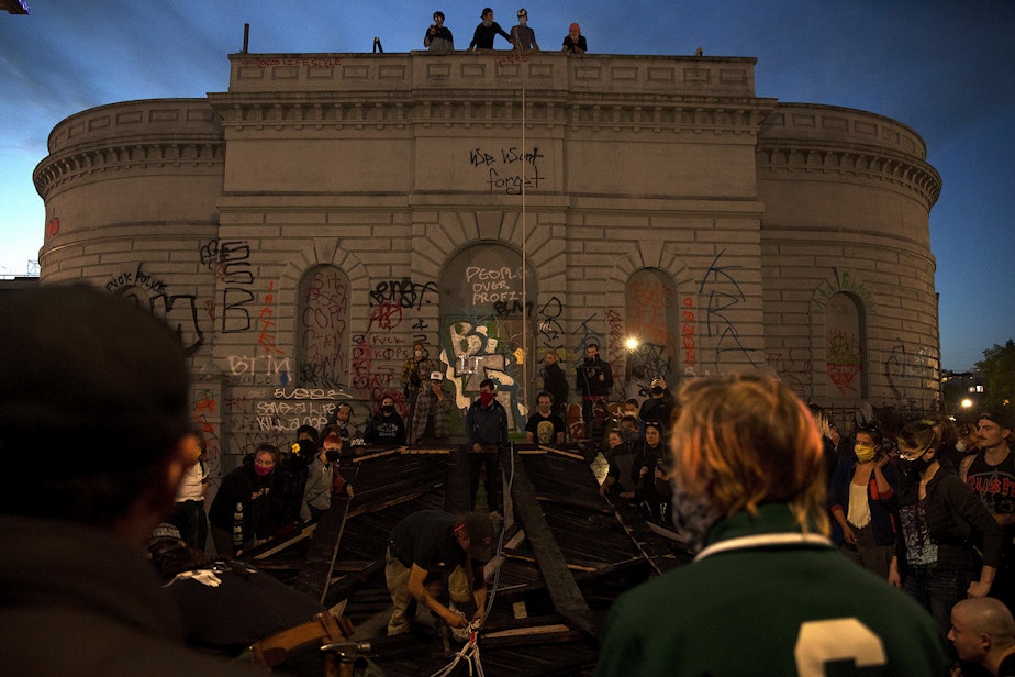 caption: A crowd gathers around a Black Power fist art instillation during an attempt to lift the structure inside the Capitol Hill Organized Protest Zone on Tuesday, June 16, 2020, in Seattle. As a result of safety concerns, the group decided to lift the heavy structure the following day instead.