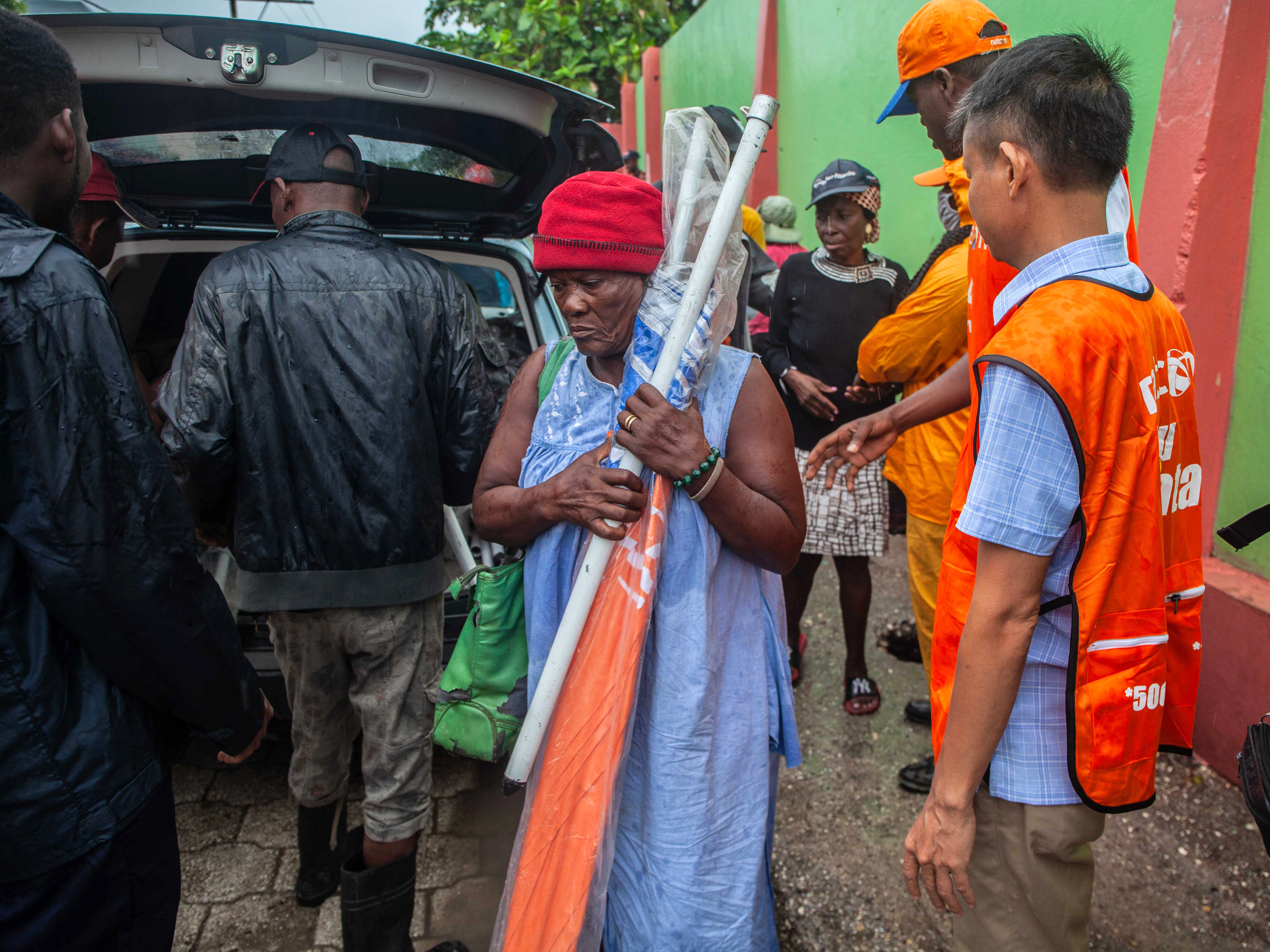 caption: Haitians receive umbrellas as part of humanitarian aid after a 7.2 magnitude earthquake struck Haiti on Aug. 14.