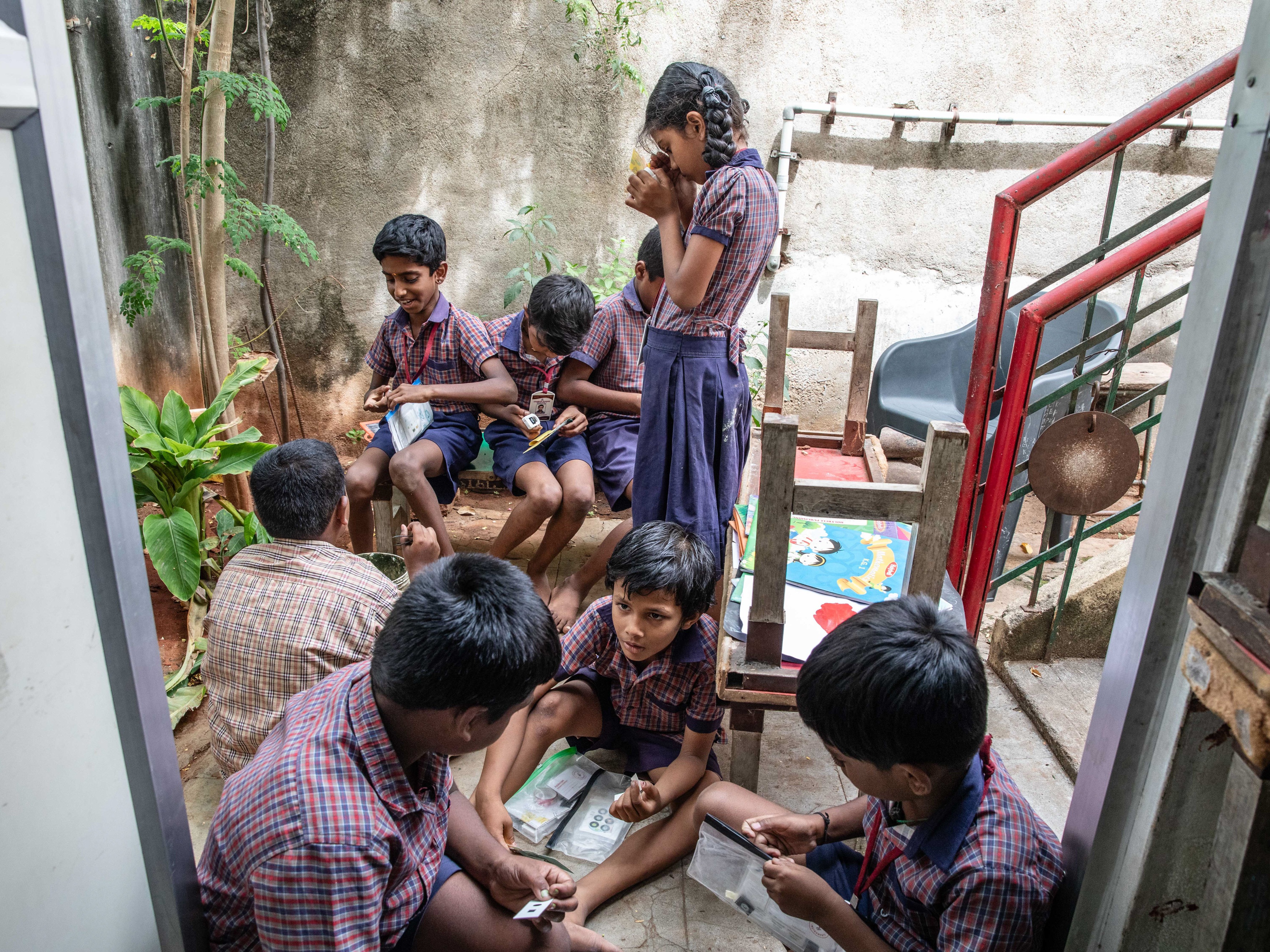 caption: Students at Eden School in northern India prepare specimens they've collected to examine in the Foldscope. The paper microscope, invented a decade ago, is given for free for schools in lower resource countries, giving students a different perspective on specimens from ants to pollen.