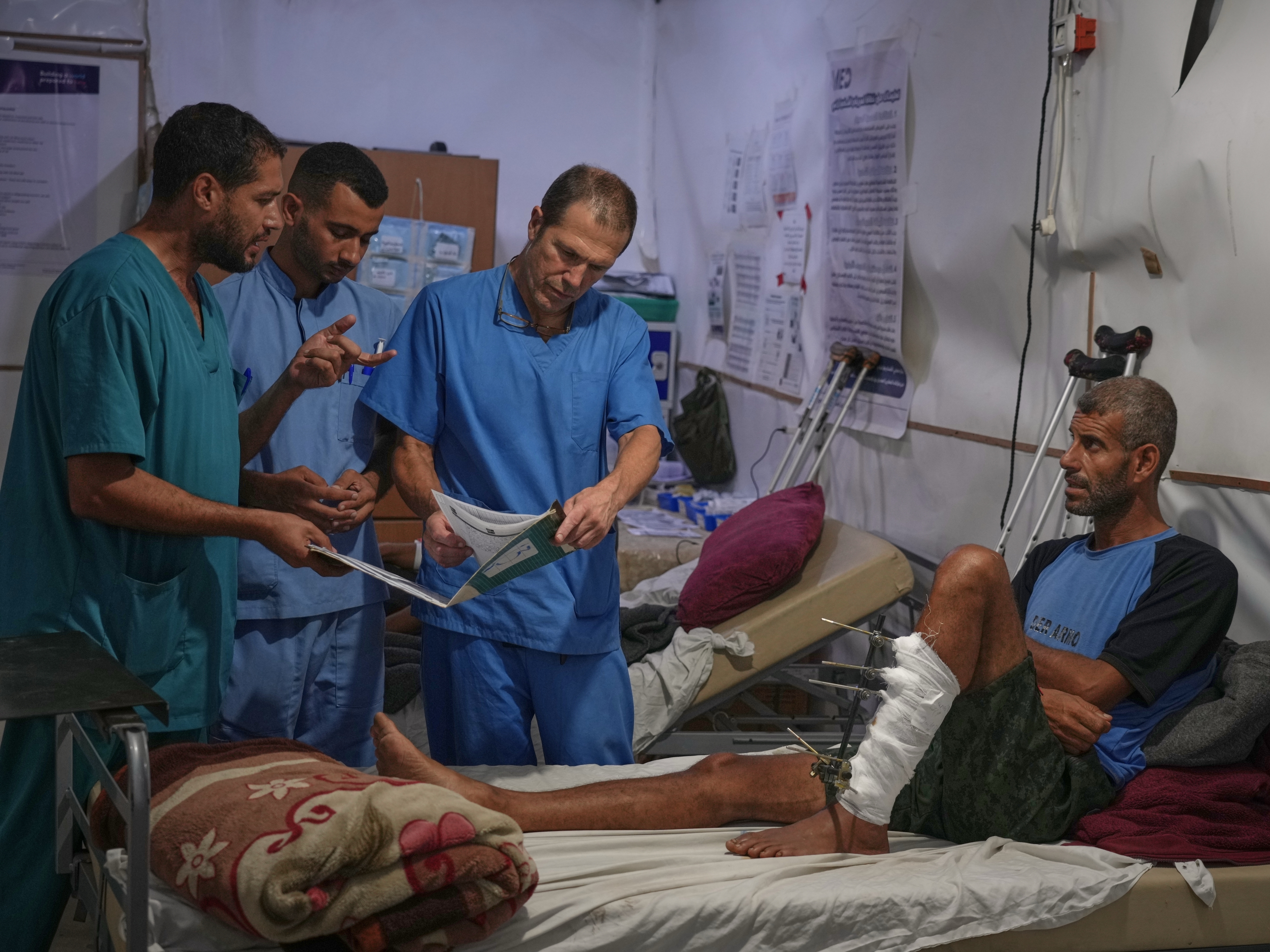 caption: Dr. Paul Ransom of the British humanitarian medical NGO UK-Med, assisted by local medical staff, treats patients at a field hospital in Muwasi, near Khan Younis in the southern Gaza Strip, Saturday, Sept. 27, 2025.