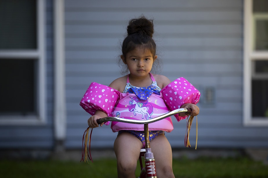 caption: Vay, 5, rides a bicycle outside of the family's apartment complex on Friday, July 15, 2022. 