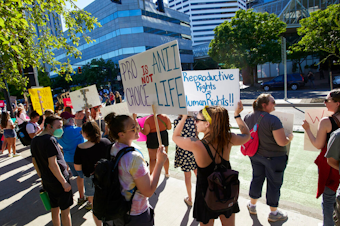 caption: Protesters hold signs demonstrating against the Supreme Court's decision to overturn Roe v. Wade in Portland, Ore., Friday, June 24, 2022. The Supreme Court has ended constitutional protections for abortion that had been in place nearly 50 years, a decision by its conservative majority to overturn the court's landmark abortion cases. 