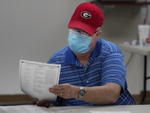 caption: A Georgia election official examines a ballot during that state's hand-count audit in 2020.