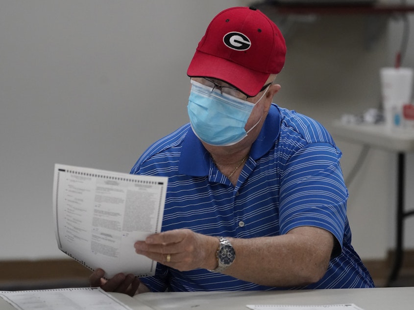 caption: A Georgia election official examines a ballot during that state's hand-count audit in 2020.