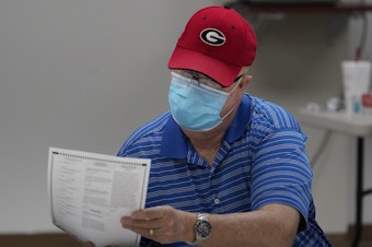 caption: A Georgia election official examines a ballot during that state's hand-count audit in 2020.