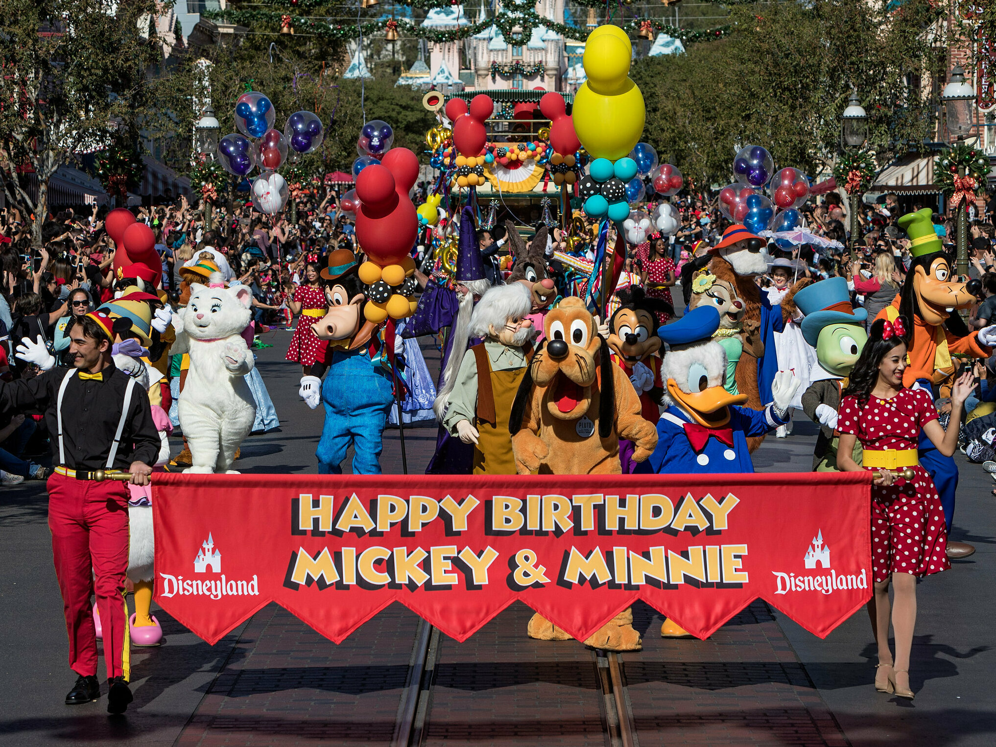 caption: Disney characters lead a parade to celebrate Mickey Mouse's 90th birthday at Disneyland in November 2018.