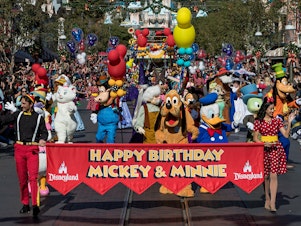 caption: Disney characters lead a parade to celebrate Mickey Mouse's 90th birthday at Disneyland in November 2018.