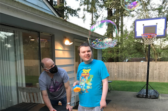 caption:  Andrew Simmons, right, blows bubbles with his father Bo last spring. Andrew, who's profoundly autistic and mostly non-verbal, lives in a supported living home in Snohomish County operated by Aacres WA, a troubled state contractor. Bo Simmons says conditions in the home over the past year have deteriorated to the point of being dangerous for Andrew and his housemates. 