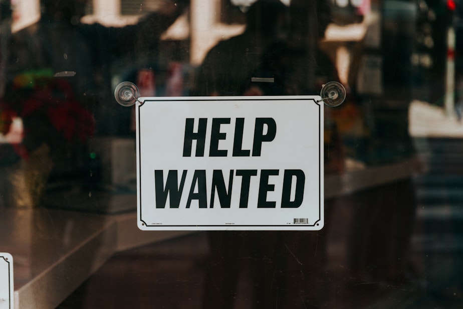 A help wanted sign hangs in the window