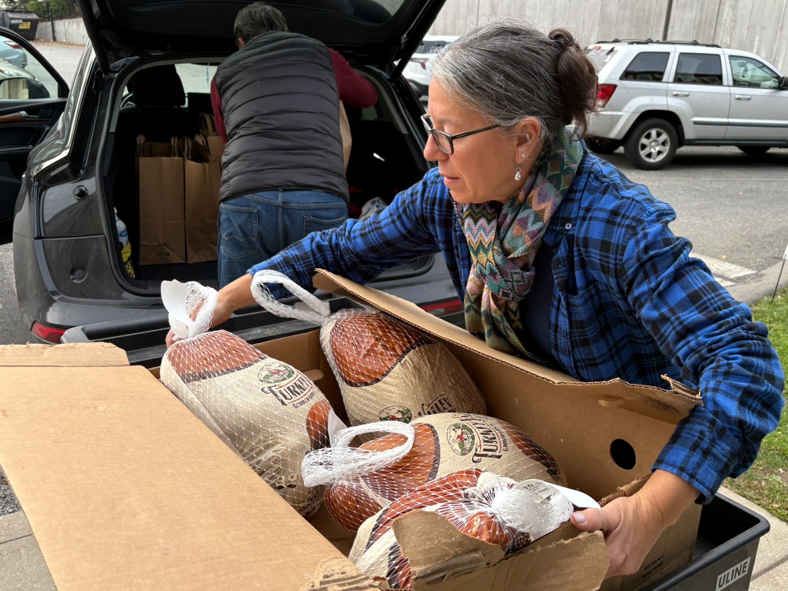 caption: Julie Miller helps deliver frozen turkeys ahead of Thanksgiving. She is one of several volunteers helping the ABCD Allston/Brighton Neighborhood Opportunity Center in Boston. Demand there has spiked since SNAP benefits have lapsed, and some people looking for food assistance have to wait two weeks for help.