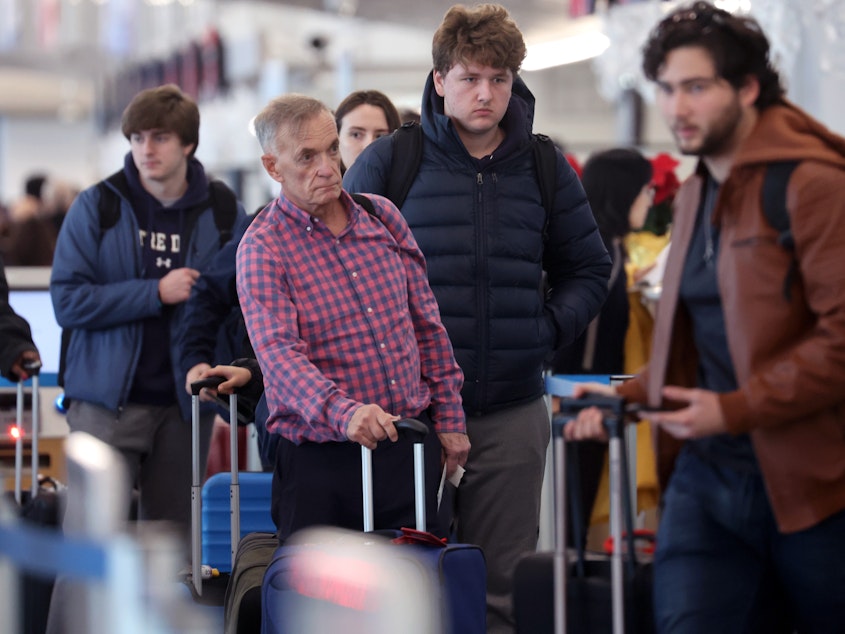 caption: Travelers arrive for flights at O'Hare International Airport in Chicago on Dec. 16.