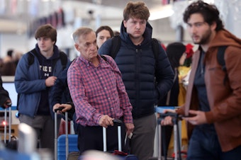 caption: Travelers arrive for flights at O'Hare International Airport in Chicago on Dec. 16.