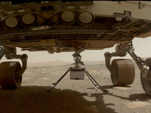 caption: NASA's Ingenuity helicopter with all four of its legs deployed before dropping from the belly of the Perseverance rover on March 30, 2021.