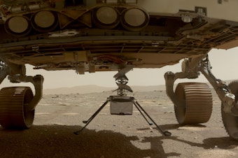 caption: NASA's Ingenuity helicopter with all four of its legs deployed before dropping from the belly of the Perseverance rover on March 30, 2021.
