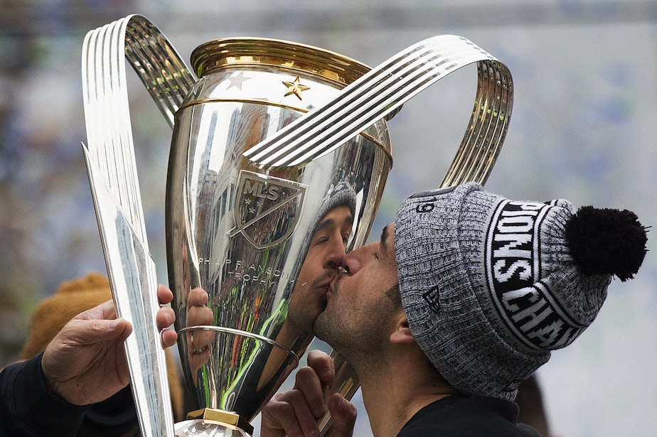 caption: Seattle Sounders team captain Nicolás Lodeiro kisses the MLS Championship Cup on Tuesday, November 12, 2019, during the MLS Cup Champions Parade and Rally near Westlake Park in Seattle.