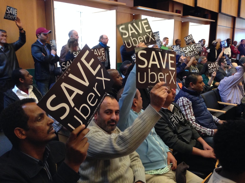 caption: Drivers and supporters of app-based rideshare service UberX pack Seattle City Council chambers.
