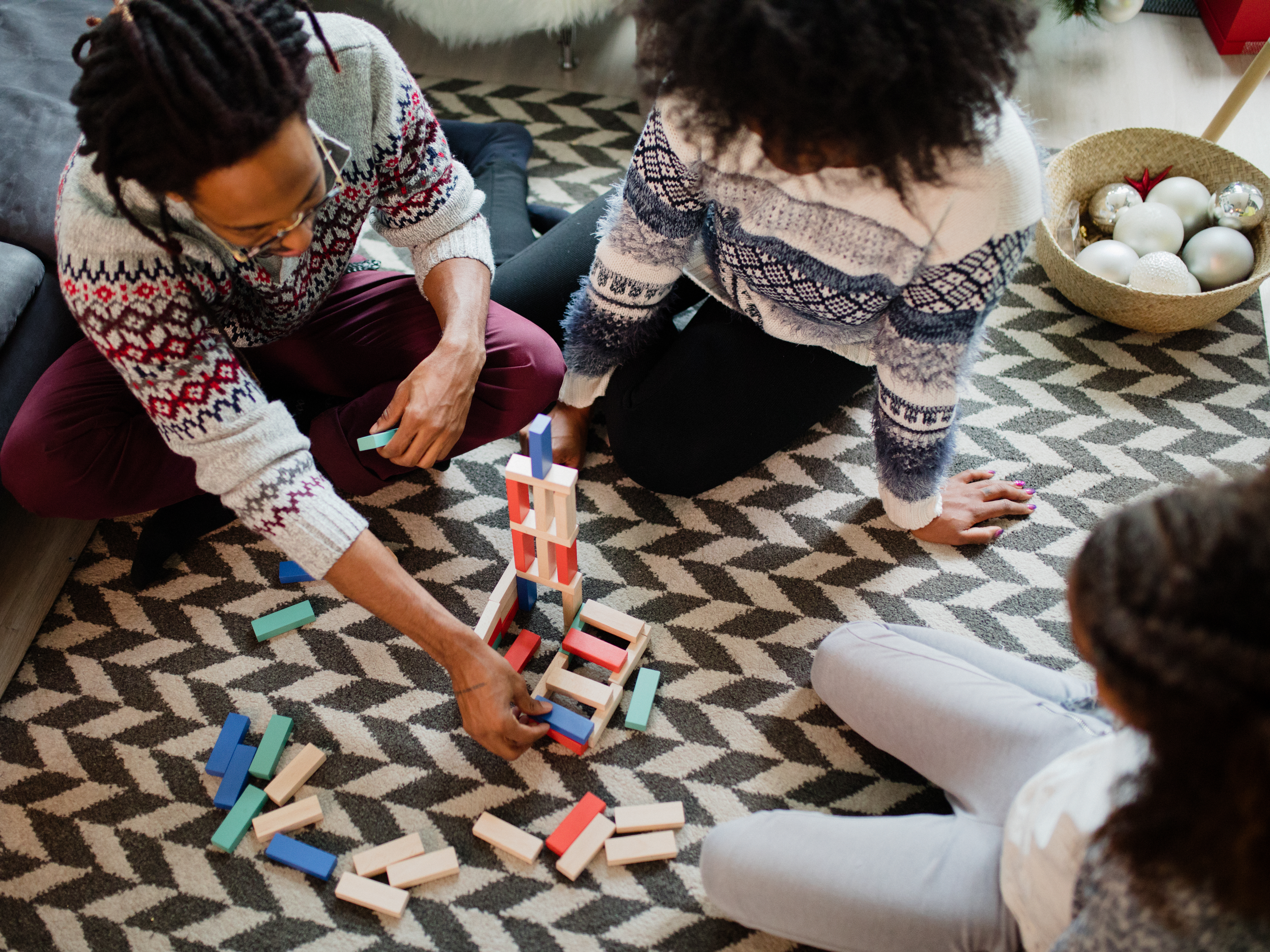 Family spending time together playing a game of stacking blocks while sitting on the carpet