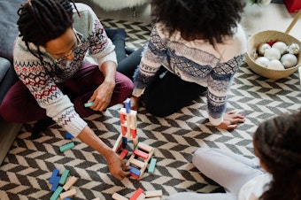 Family spending time together playing a game of stacking blocks while sitting on the carpet