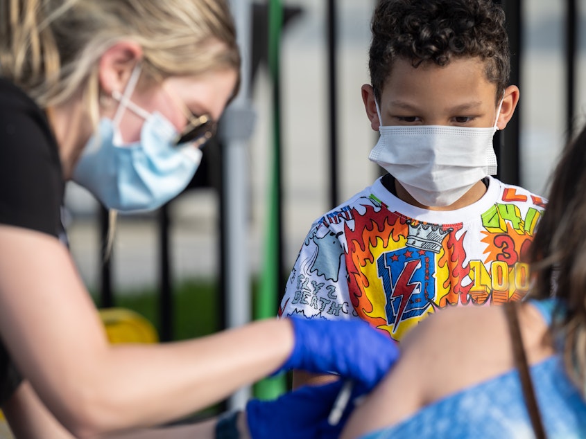 caption: A child watches as a nurse administers a shot of COVID-19 vaccine during a pop-up vaccination event at Lynn Family Stadium on April 26, 2021 in Louisville, Kentucky.