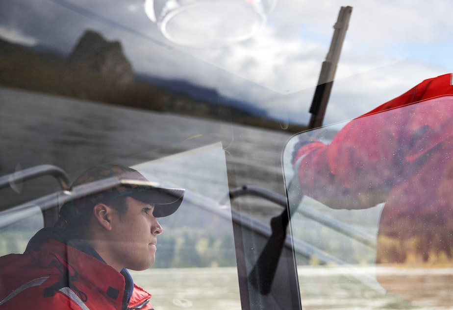 caption: Devayne Lewis, a fishery technician with the Columbia River Inter-Tribal Fish Commission operates the boat while Teddy Walsey, right, looks for sea lions during a non-lethal hazing mission where shell crackers and sticks of dynamite are used to scare sea lions away from the area on Friday, April 12, 2019, near the Bonneville Dam. 