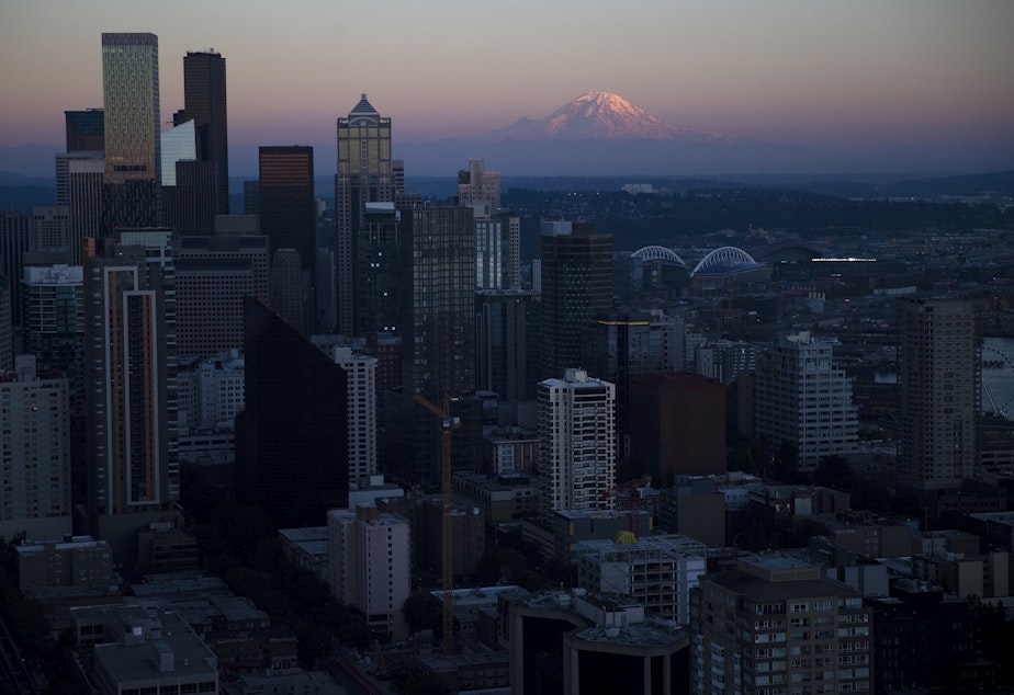 caption: Downtown Seattle is shown as the sun sets over Mt. Rainier on Monday, July 25, 2022, as seen from the Space Needle in Seattle. 
