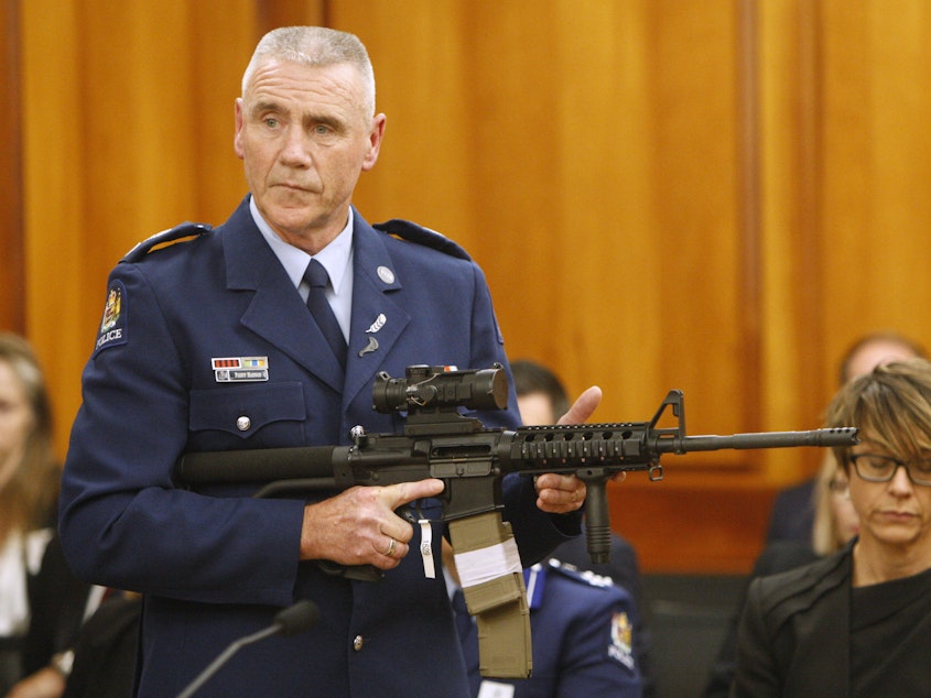 caption: Police Sr. Sgt. Paddy Hannan shows New Zealand lawmakers an AR-15 style rifle on April 2. The country's parliament voted overwhelmingly Wednesday to ban most semi-automatic weapons after a gunman slaughtered 50 people at a mosque in March.