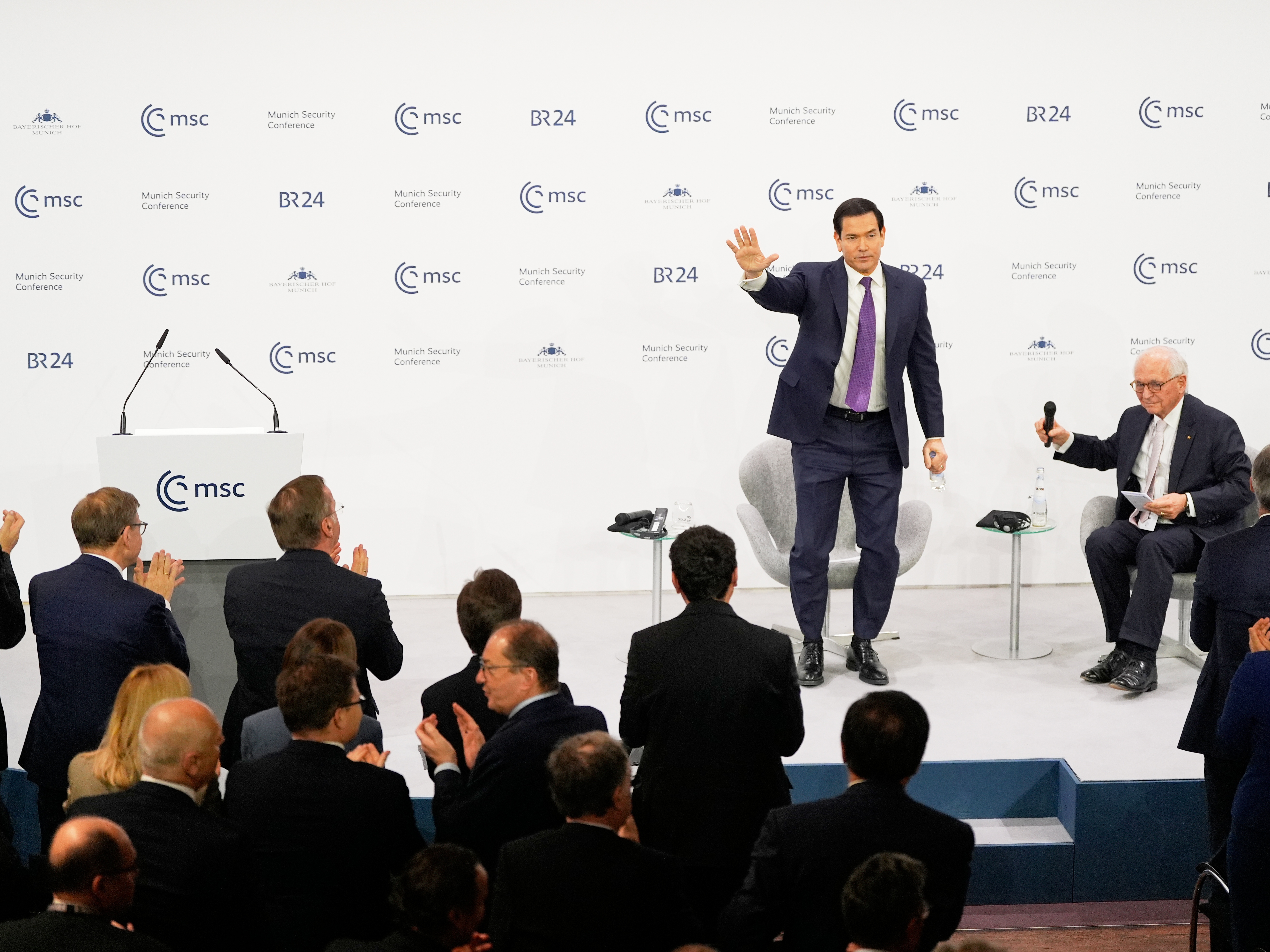 caption: U.S. Secretary of State Marco Rubio waves, next to Chairman of the Munich Security Conference Wolfgang Ischinger, as he gets a standing ovation after his speech at the Munich Security Conference in Munich, Germany, on Saturday.