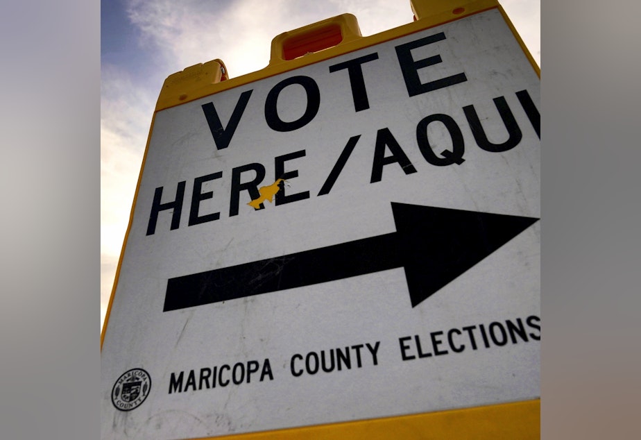 caption: In this file photo, voters deliver their ballot to a polling station in Tempe, Ariz., on Nov. 3, 2020. In the 2024 presidential preference election in Arizona, independent voters are not permitted to vote.