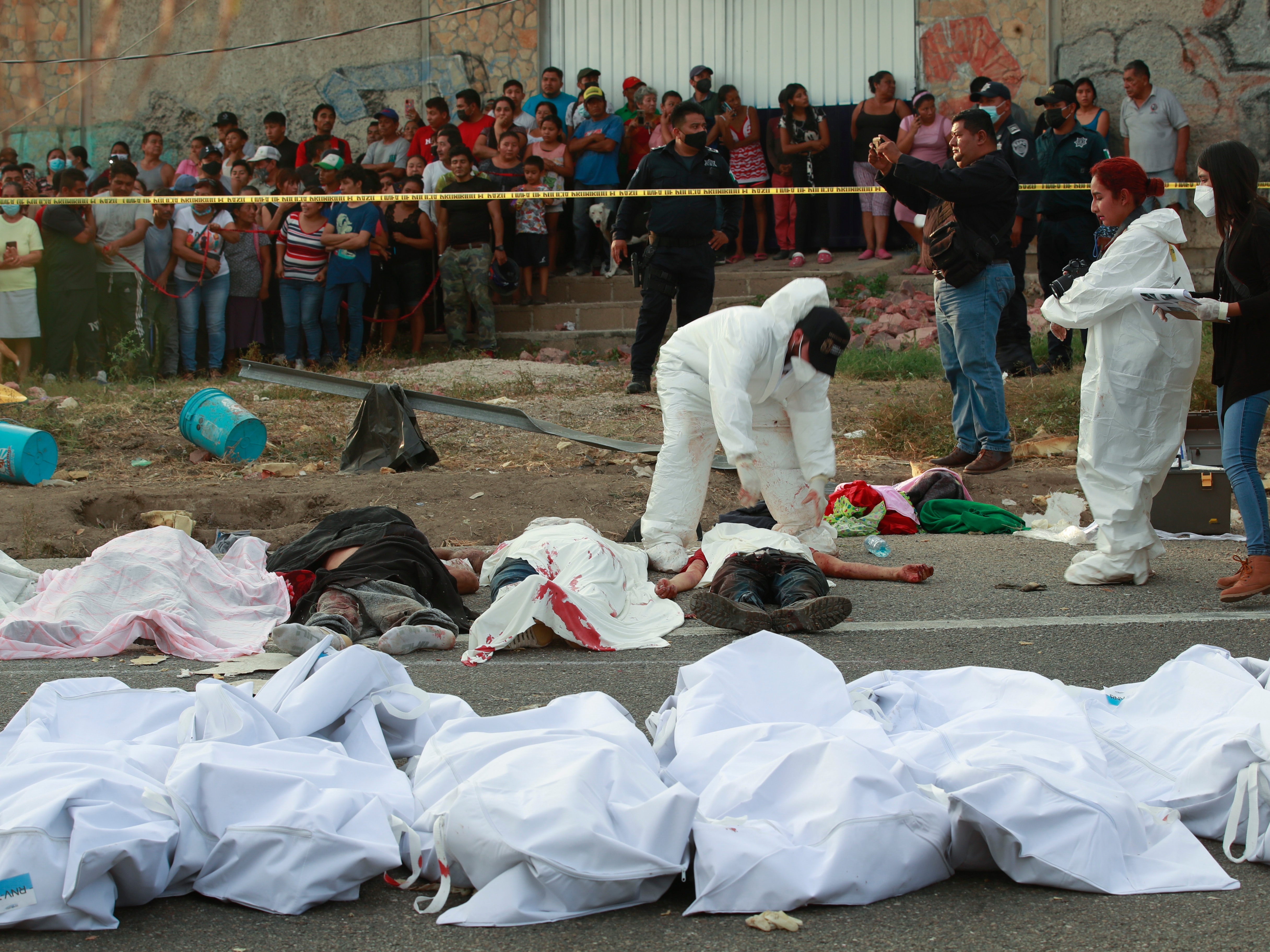 caption: Bodies in bags sit on the side of the road after a deadly semi-trailer truck crash in Tuxtla Gutierrez, Chiapas state, Mexico, Dec. 9, 2021.