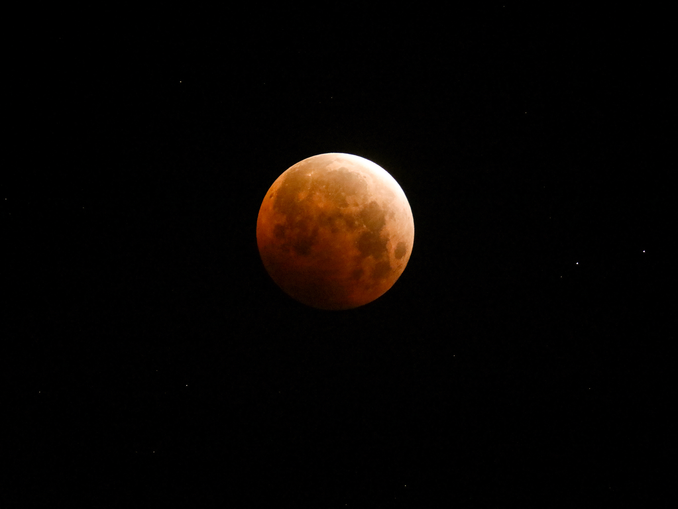 caption: Light shines from a total lunar eclipse over Santa Monica Beach, Calif., in May 2021.