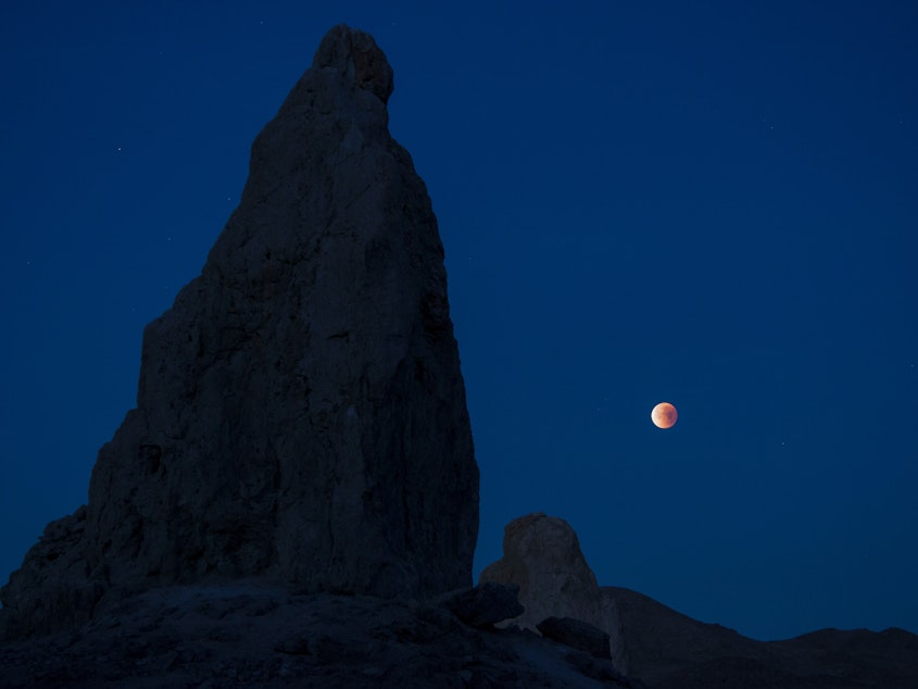 caption: A lunar eclipse viewed from California's Trona Pinnacles Desert National Conservation Area. Scientists believe there may be more moons in the galaxy than planets.