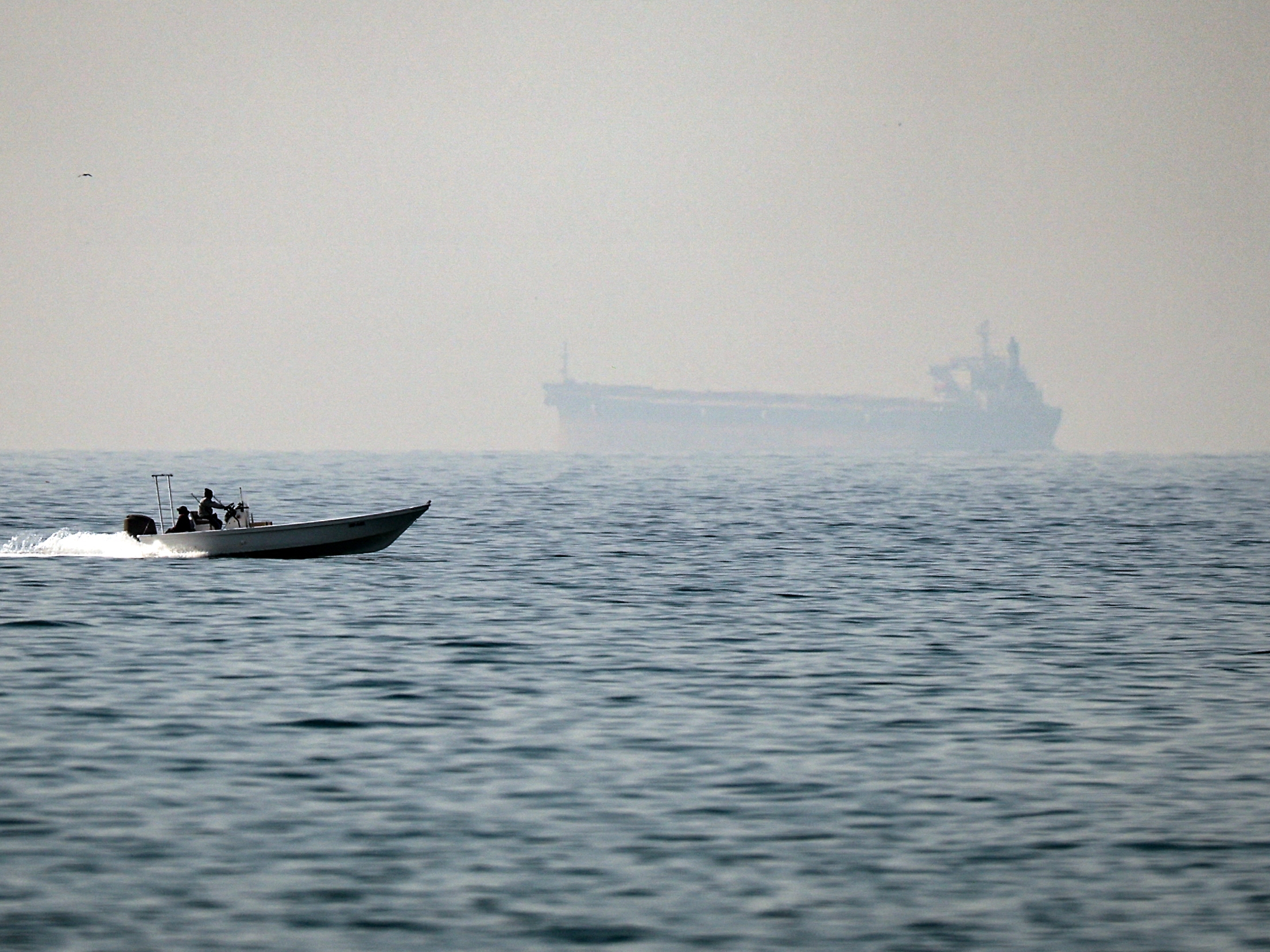 caption: A motorboat cruises off the coast of the United Arab Emirates, on the Strait of Hormuz, with a tanker seen in the background, on February 25, 2026. Tanker traffic through the strait has come essentially to a stop after Iran declared the strait closed following attacks on Iran by the U.S. and Israel.