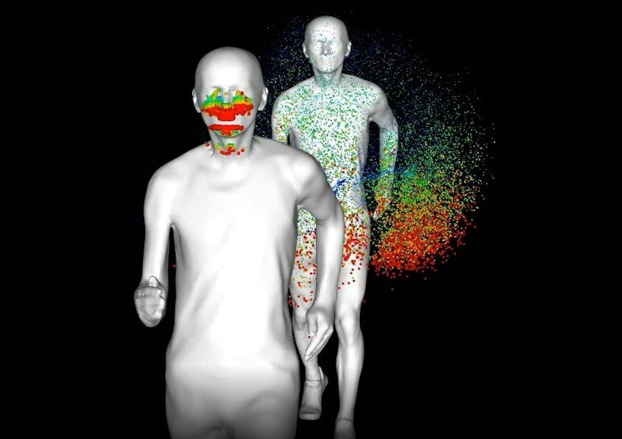 caption: Screengrab of simulation of a runner's exhalation splattering a runner behind him. Red represents the largest droplets, while blue represents the smallest.