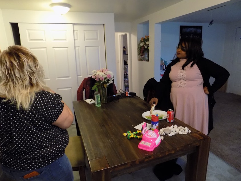 caption: Case manager Vera Page, right, visits with one of her clients