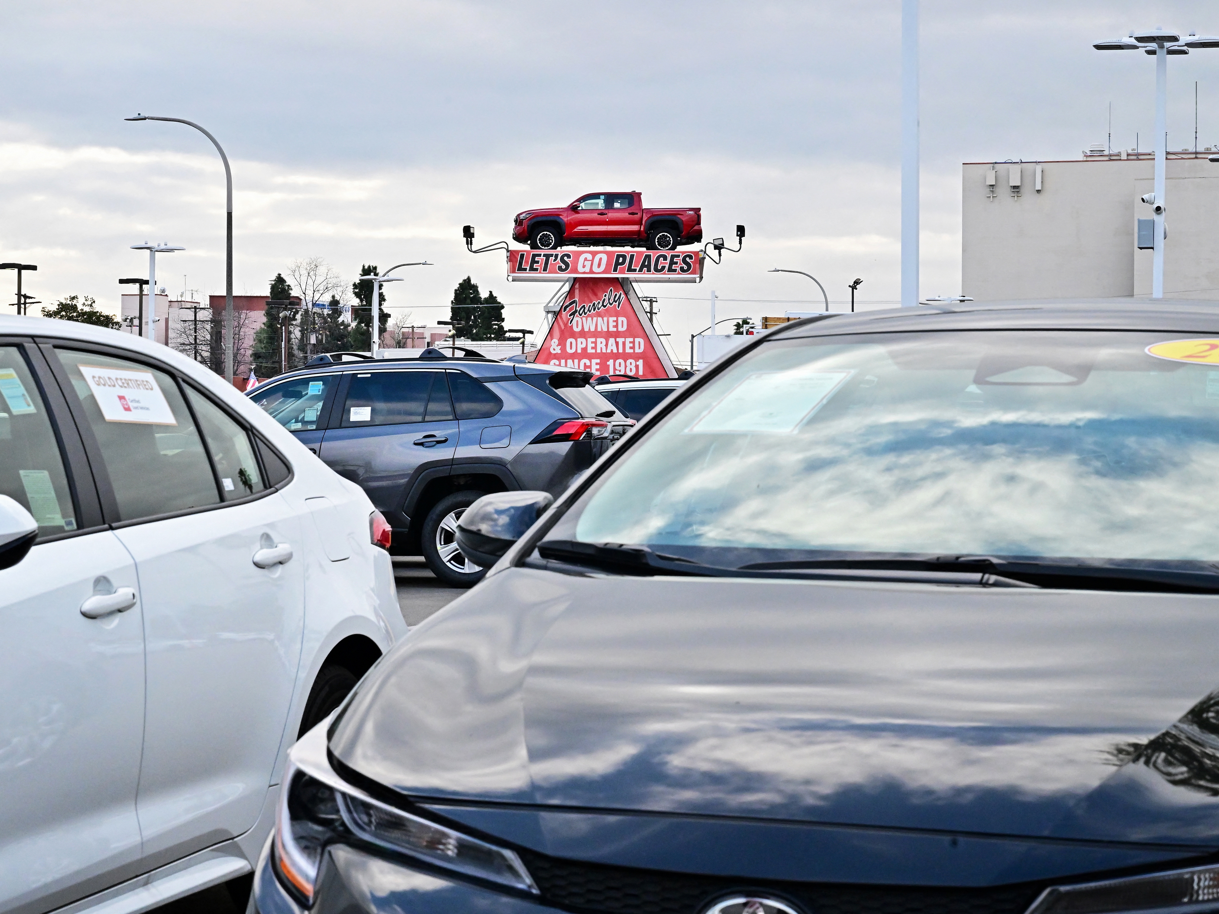caption: A pickup truck is raised for display at a car dealership in Alhambra, California, on March 27, 2025. After President Trump announced significant tariffs on imported vehicles and parts, automaker stocks fell sharply. But sales at dealerships rose, at least in the short-term, as buyers try to get ahead of the anticipated price spikes in the coming months.