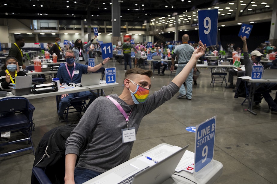caption: Volunteer Joel Metschke calls for the next patient to be vaccinated against Covid-19 at the mass vaccination site at Lumen Field Event Center on Saturday, March 13, 2021, in Seattle.
