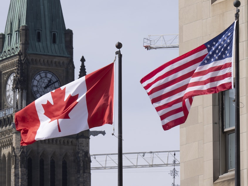 caption: The Canadian and U.S. flags are displayed on lamp posts in the downtown area, March 22, 2023, near Parliament Hill in Ottawa, Ontario.