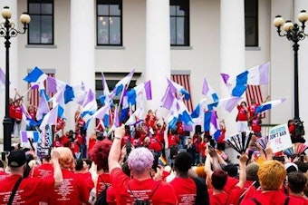 caption: Advocates outside Florida's historic Capitol wave drag pride flags during the Drag Queens March in 2023.