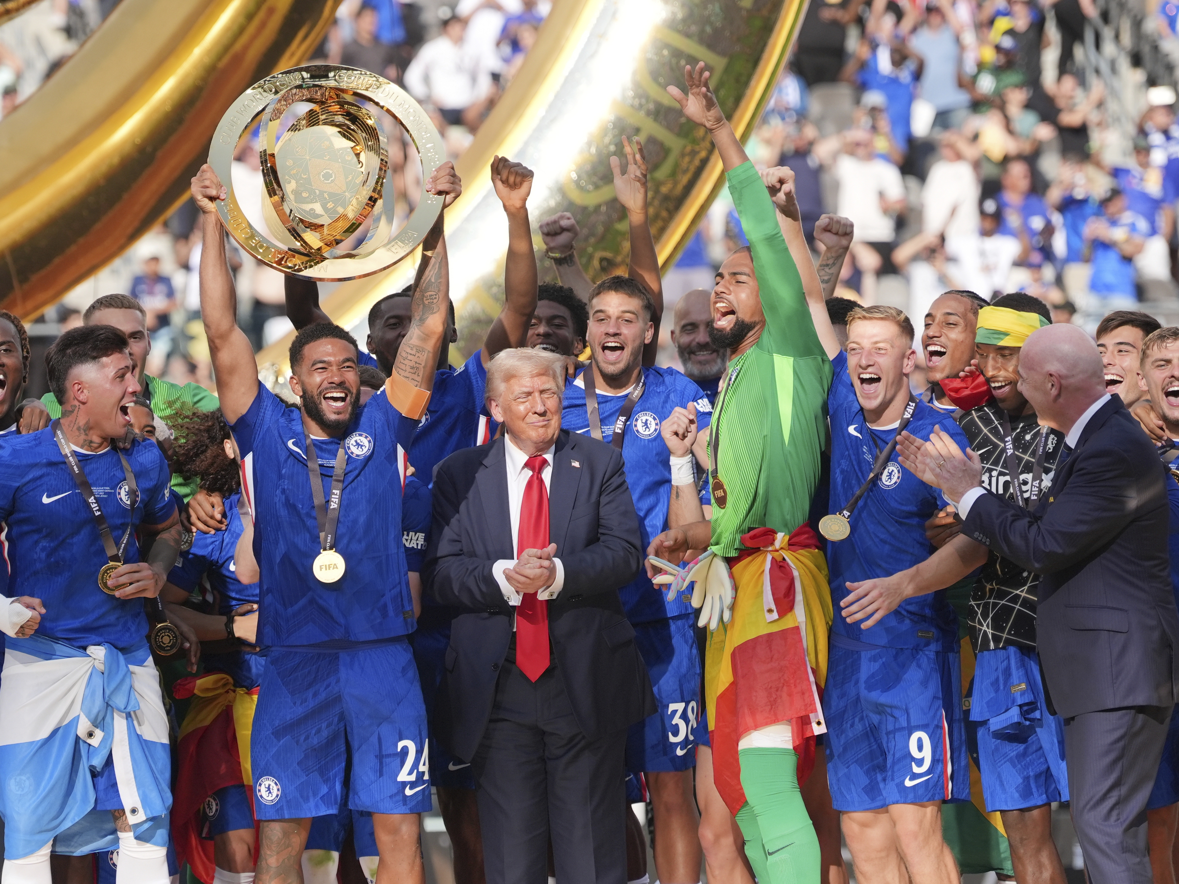 caption: Chelsea's Reece James (24) lifts the trophy as President Donald Trump looks on following the Club World Cup final soccer match between Chelsea and PSG in East Rutherford, N.J. on Sunday.