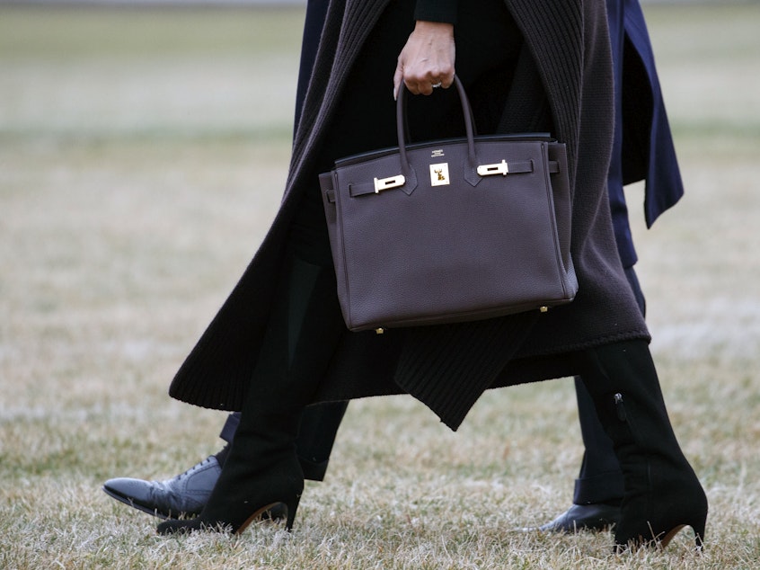caption: Former first lady Melania Trump is seen toting a Hermes handbag while walking across the South Lawn of the White House in 2019.
