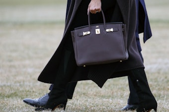 caption: Former first lady Melania Trump is seen toting a Hermes handbag while walking across the South Lawn of the White House in 2019.