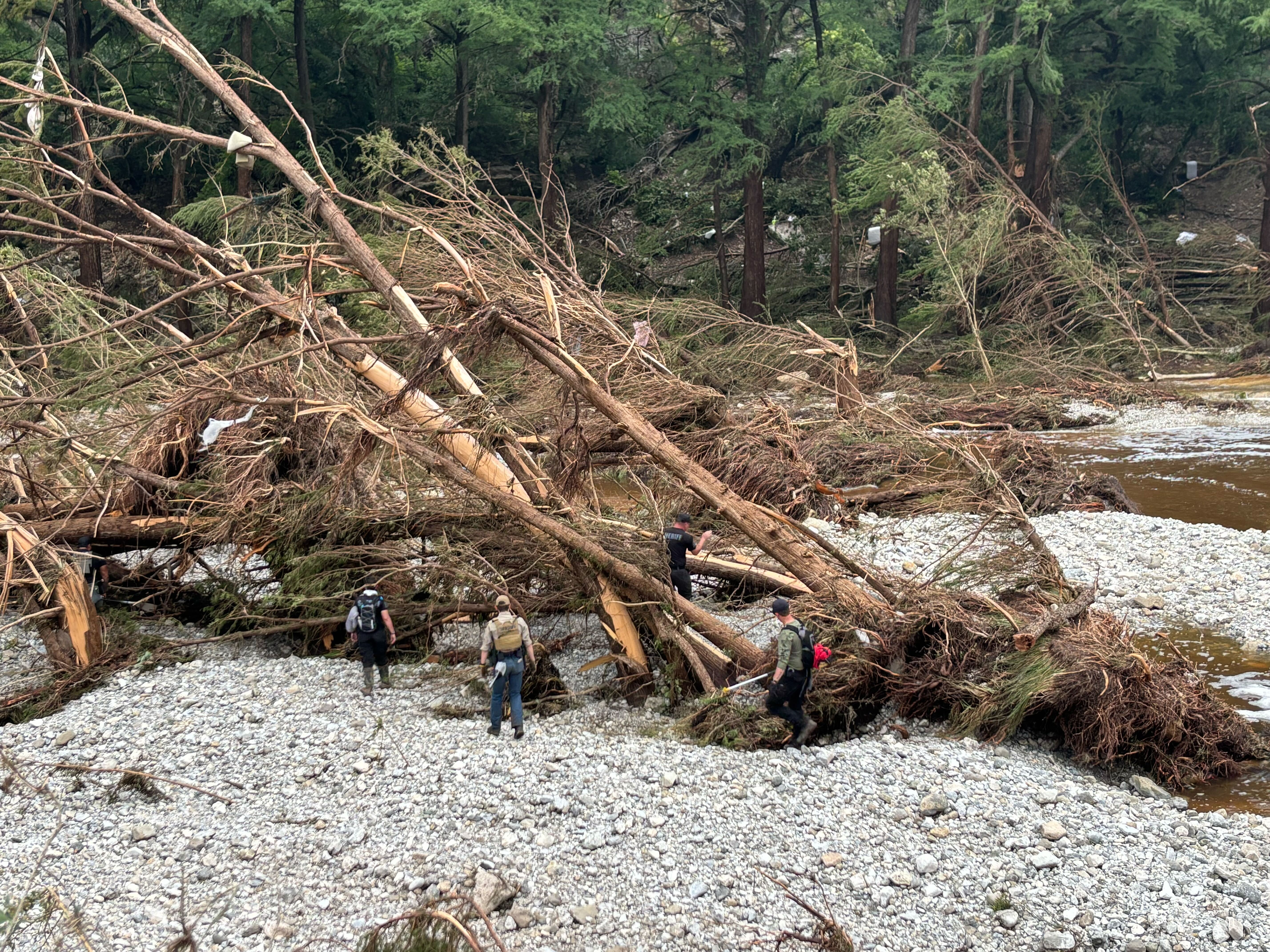 caption: First responders search for missing people near Camp Mystic, an all-girls summer camp along the Guadalupe River in Kerrville, Texas, on Saturday.