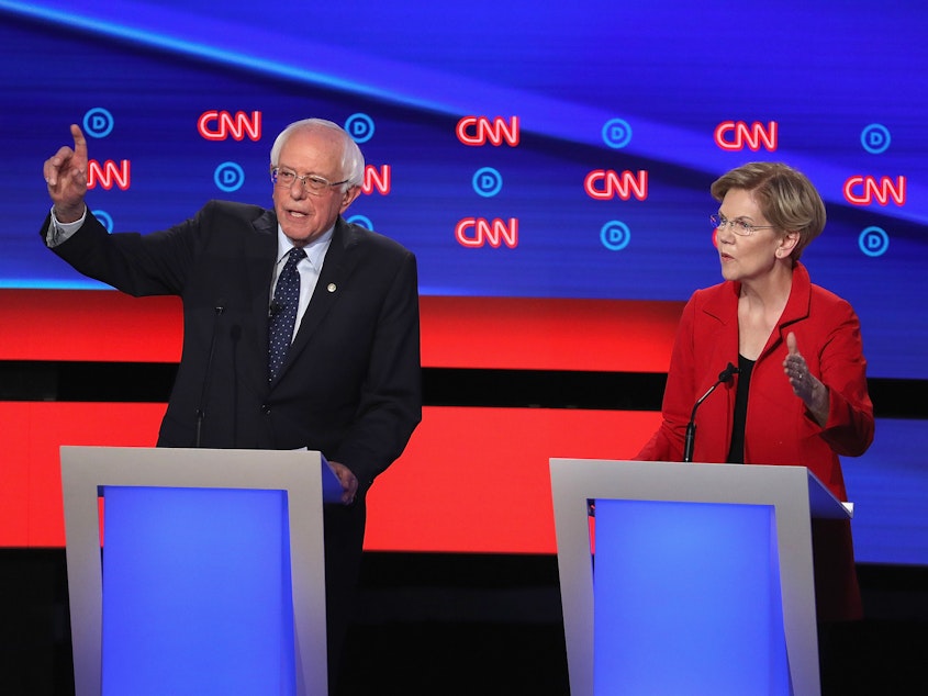 caption: Democratic presidential candidates Bernie Sanders and Elizabeth Warren say corporate America has put profits before workers by shifting jobs to other countries.
