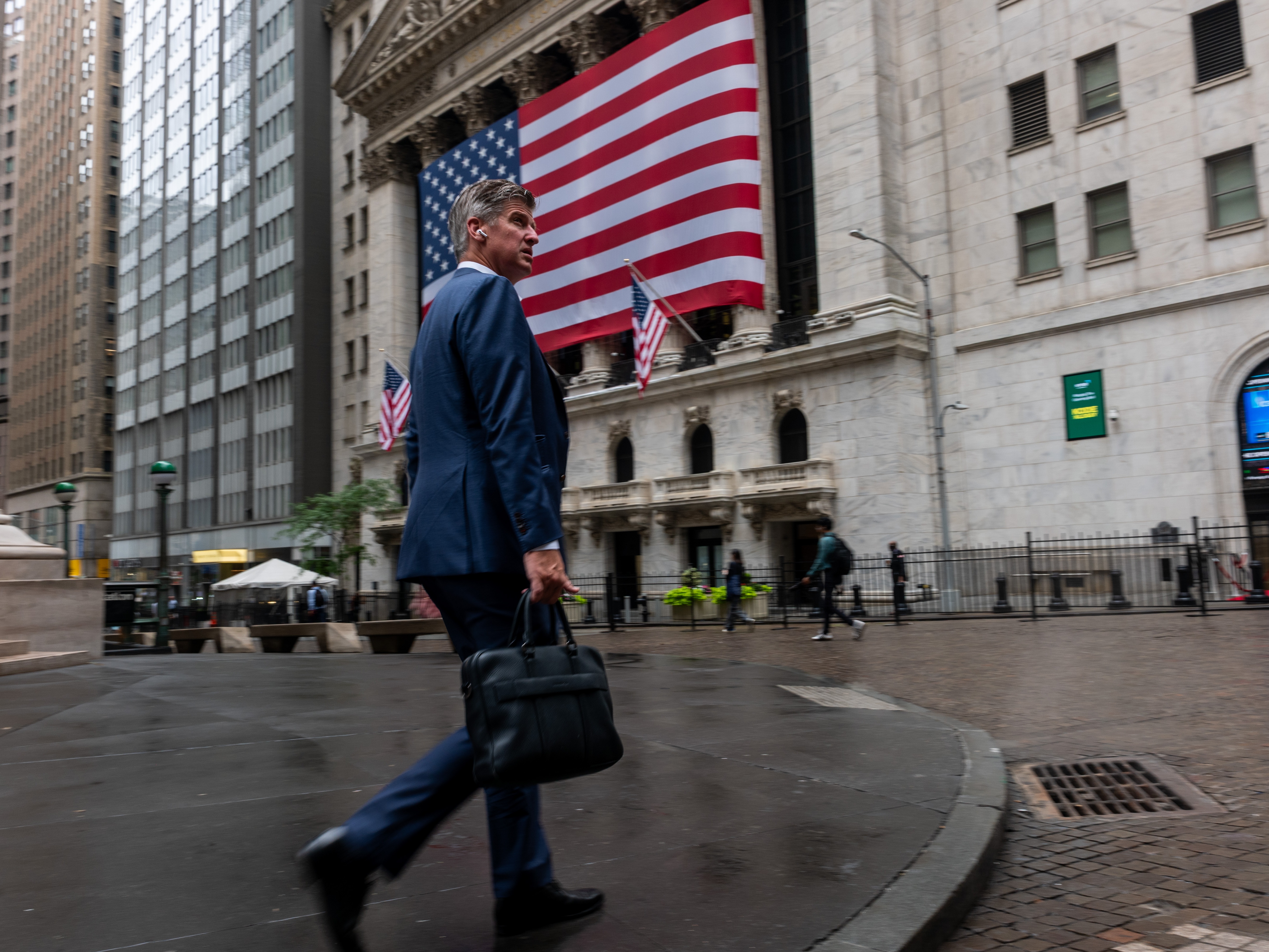 caption: A businessman walks by the New York Stock Exchange in New York City. As more than 100 big companies reported earnings this week, the S&amp;P 500 and Nasdaq hit a series of record highs.