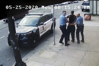 caption: This image from video shows Minneapolis police officers Thomas Lane, left, and J. Alexander Kueng, right, escorting George Floyd, center, to a police vehicle outside Cup Foods in Minneapolis, on May 25, 2020. The image was shown as prosecutor Steve Schleicher gave closing arguments in the trial of Derek Chauvin for the death of Floyd.