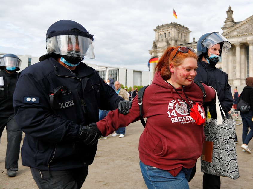 caption: Police detain a demonstrator during a protest against the government's restrictions to prevent the spread of the coronavirus, in front of the Reichstag, in Berlin, Germany, on Saturday.