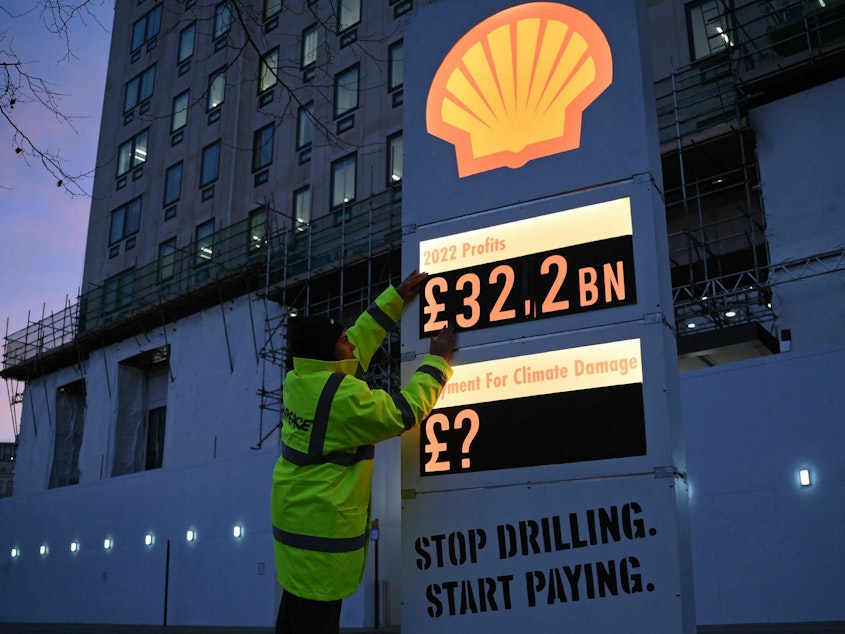 caption: Activists from Greenpeace set up a mock-petrol station price board displaying the Shell's net profit for 2022.
