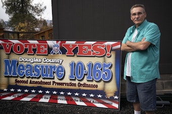 caption: <p>Tom McKirgan stands in front of his house with a campaign sign supporting the Douglas County Second Amendment Preservation Ordinance on Oct. 23, 2018 in Camas Valley, Oregon. McKirgan is a member of the Three Percenter militia and helped write the Douglas County ordinance.</p>