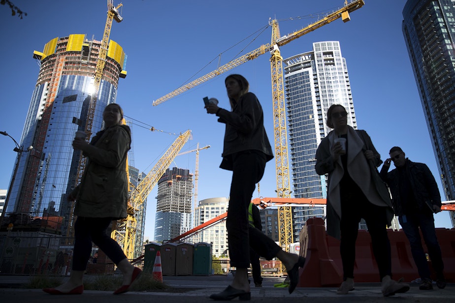 caption: People walk on 7th Ave., in front of construction and cranes on Tuesday, October 24, 2017, in Seattle.